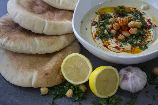 Egy tányér friss, házi készítésű hummus pitakenyérrel az asztalon. A Közel-Kelet autentikus étele. Egészséges étkezési koncepció. Vegán kiegyensúlyozott étel. Izrael hagyományos lisztje.  - Fotó, kép