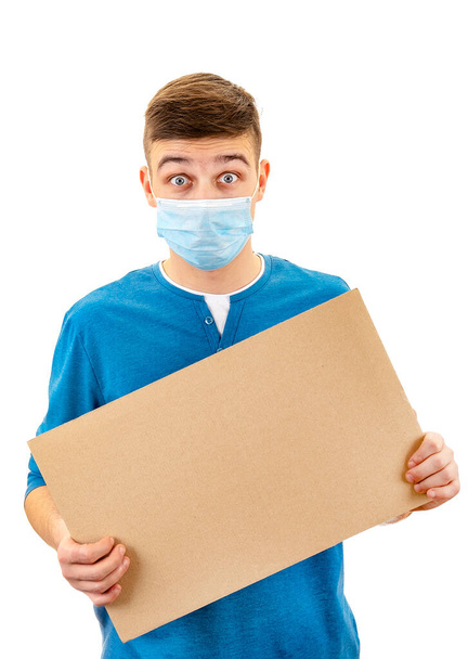 Surprised Young Man in Flu Mask hold a Cardboard Isolated on the White Background - Valokuva, kuva