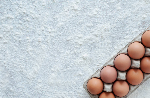 Fondo para hornear. Huevos y harina espolvoreada sobre la mesa. vista desde arriba. espacio de copia
. - Foto, Imagen