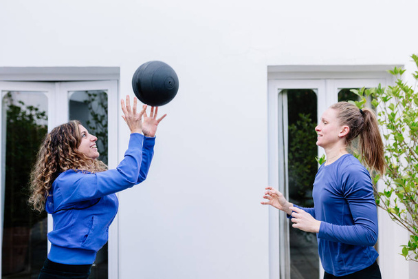 Due giovani donne che fanno esercizio fisico insieme a palla medica su una terrazza
 - Foto, immagini
