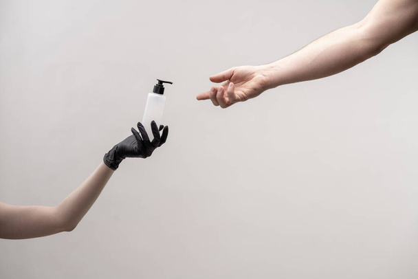 Hand with dispenser of sterilizer transfers to another female hand - Zdjęcie, obraz