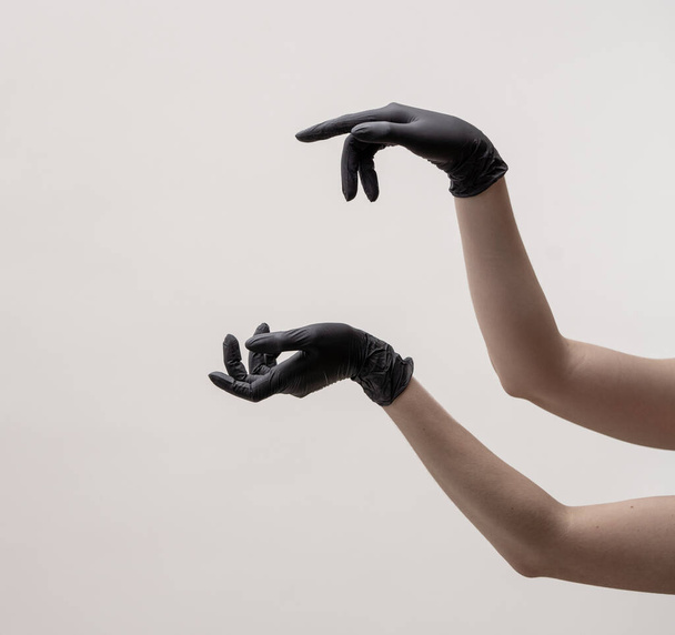 Hands in black silicone gloves on a light background. - 写真・画像