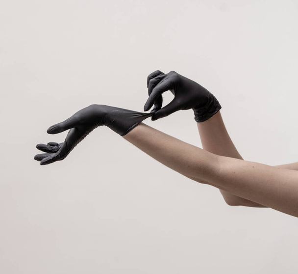 Hands in black silicone gloves on a light background. - 写真・画像