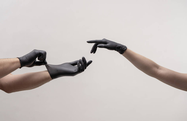 Male and female hand in black gloves stretch to touch each other. - Foto, imagen