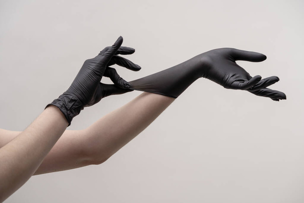 Hands in black silicone gloves on a light background. - Foto, imagen