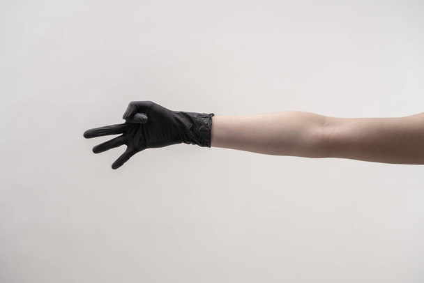 Hands in black silicone gloves on a light background. - Foto, imagen