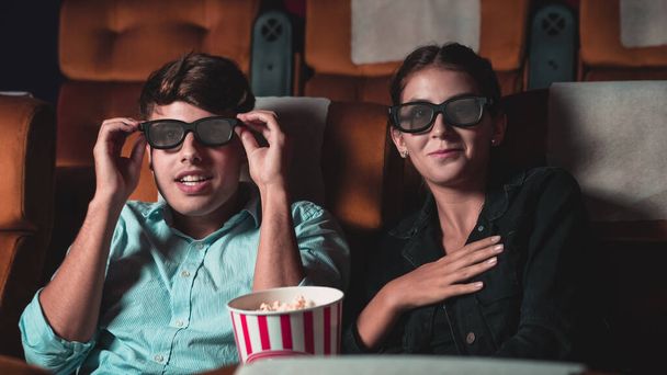 Чоловік і жінка в кіно дивиться фільм з 3D окулярами. з цікавістю дивиться на екран, захоплюючим і їдять попкорн
 - Фото, зображення