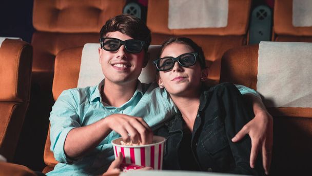 Uomo e donna al cinema che guardano un film con occhiali 3D. con interesse guardando lo schermo, eccitante e mangiare popcorn - Foto, immagini