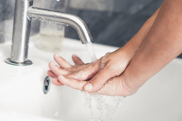 Hands washing for prevention of novel Coronavirus Disease 2019 or COVID-19 . People wash hands at bathroom sink to clean the virus infection. - 写真・画像