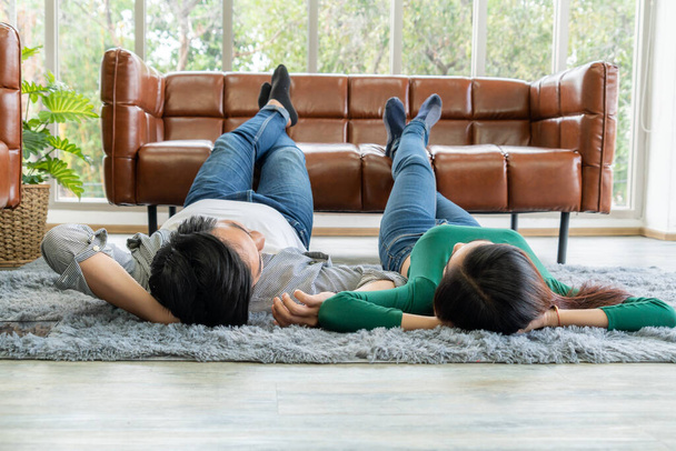 幸せなアジアのカップルのカーペットの上のリビングルームの床に横たわっ。恋愛関係とライフスタイルのコンセプト. - 写真・画像