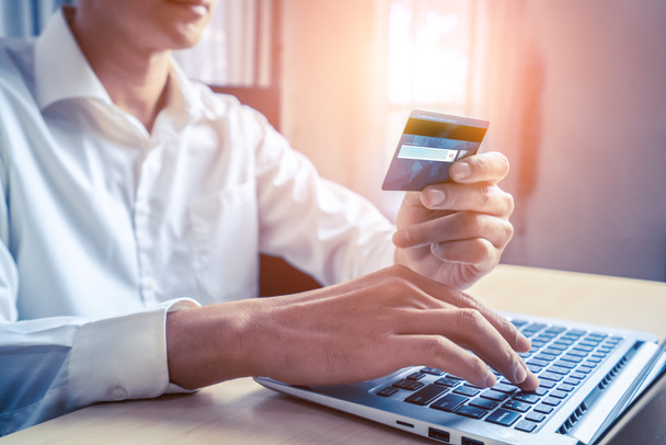 Νεαρός άντρας χρησιμοποιούν πιστωτική κάρτα για online αγορές πληρωμής σε εφαρμογή ή ιστοσελίδα υπολογιστή laptop. Έννοια του ηλεκτρονικού εμπορίου και των ηλεκτρονικών αγορών. - Φωτογραφία, εικόνα