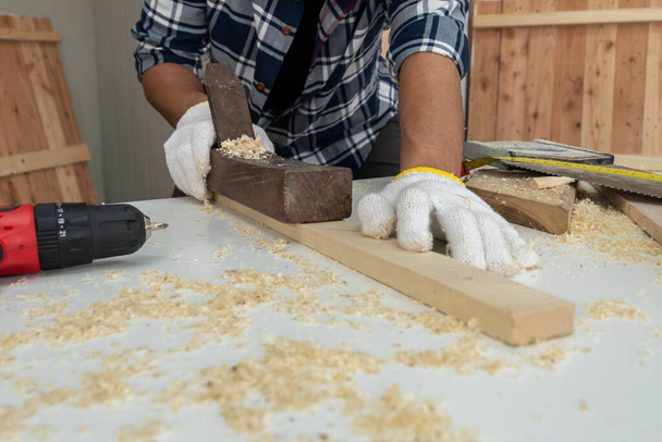 Ξυλουργός που εργάζεται σε ξυλουργείο για την παραγωγή οικοδομικών υλικών ή ξύλινων επίπλων. Ο νεαρός Ασιάτης ξυλουργός χρησιμοποιεί επαγγελματικά εργαλεία για χειροτεχνία. DIY maker και ξυλουργική έννοια εργασίας. - Φωτογραφία, εικόνα