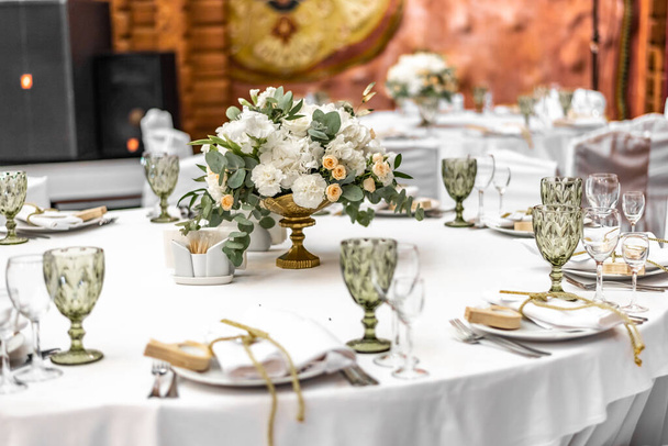 Λευκή γαμήλια διακόσμηση στο εστιατόριο. Πολυτελής γαμήλια συμφωνία. Διακόσμηση γάμου. Τραπέζια σε εστιατόριο διακοσμημένα με όμορφες λευκές παιώνιες και τριαντάφυλλα - Φωτογραφία, εικόνα