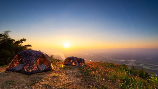 Landschap van zonsopgang of zonsondergang boven tent in natiepark. Concept camping of picknick met eco vakantie - Foto, afbeelding