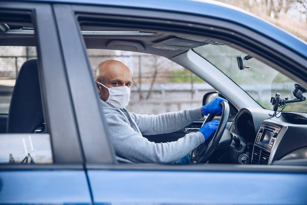 Man in protective medical mask driving a car - Fotografie, Obrázek