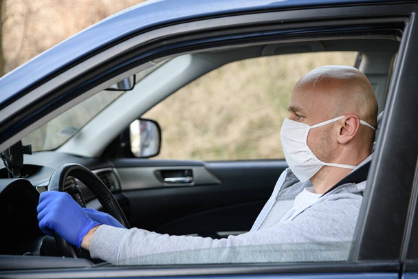 Человек за рулем автомобиля в медицинской защитной маске
. - Фото, изображение