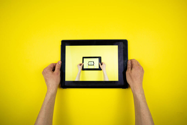 Tablet in der Hand auf gelbem Hintergrund. Bild in Bild - Foto, Bild