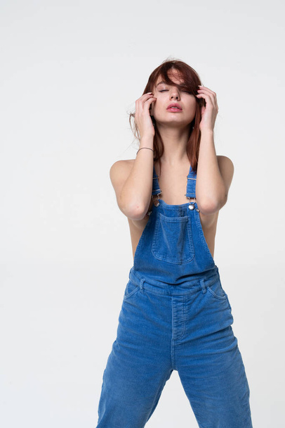 young beautiful girl posing in blue overalls in the studio - Photo, Image