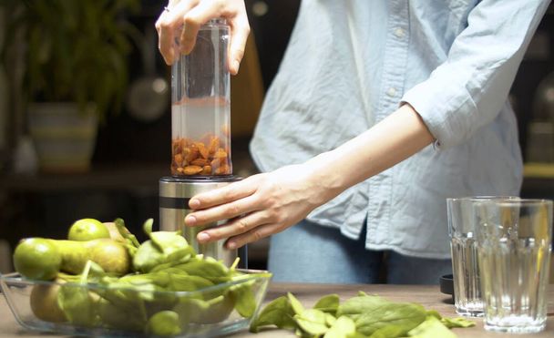 Kochen von Mandelmilch. Frau stellt Mixerglas auf einen Mixer und drückt einen Knopf. Konzept der gesunden Ernährung - Foto, Bild