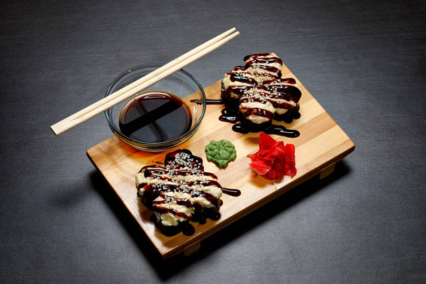 Sumo saboroso e delicioso quente e frio rola sobre a mesa. Sushi diferente - rolos com molho no conselho de cozinha japonesa
. - Foto, Imagem