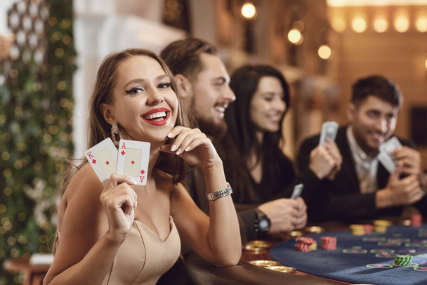 Girl with cards in her hands smiles at winning poker in a casino. - Foto, imagen