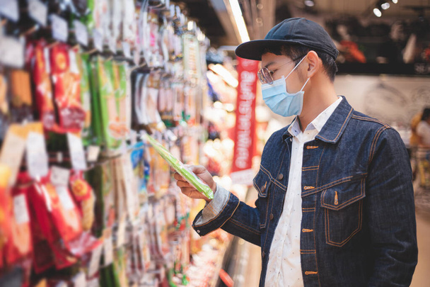 Aziatische mannen kopen en winkelen voedsel voor hamsteren tijdens de Covid uitbraak - Foto, afbeelding
