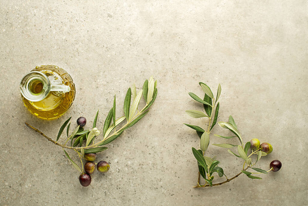 Bottle of olive oil and Branch with olives and leaves background close up. Healthy olive oil concept - Foto, imagen