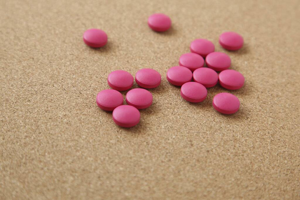 A high angle shot of some pink pills on a wooden surface - Zdjęcie, obraz