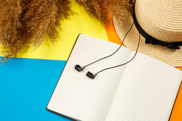 Women's accessories headphones, notebook, hat, lifestyle, woman, relax, with dry grass, decor, flat lay, style on the background. Travel, tourism concept. Beach accessories top view. - Photo, Image