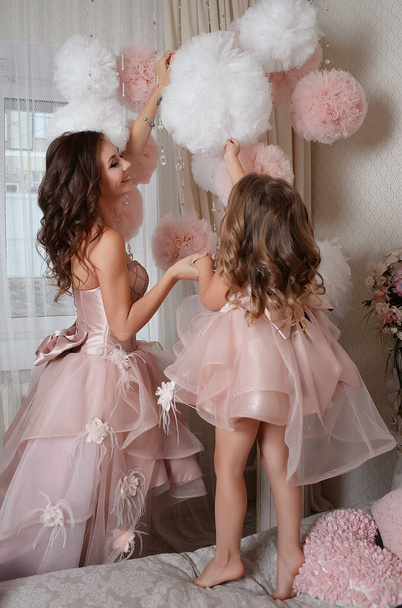 happy mother and daughter in beautiful dresses real princesses surrounded by flowers rejoice in the coming of spring - Photo, Image