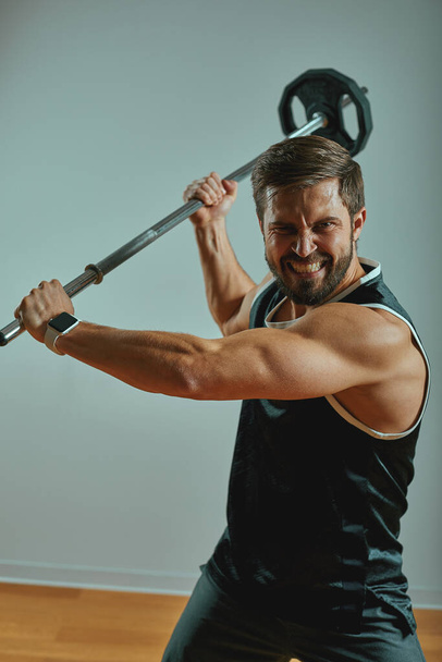 man sportsman weightlifting. Muscular man attacks with barbell - Φωτογραφία, εικόνα