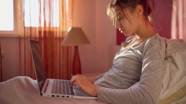 skilled female freelancer working on laptop from her home bed. - Záběry, video