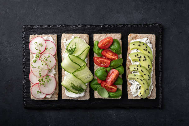 Different vegetarian sandwiches on a black background.  - Фото, зображення