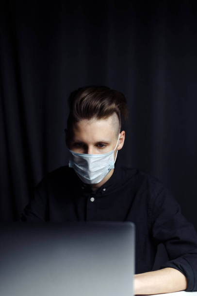 The young guy is studying distance learning and talks on the webcam at home in the evening. The concept of self-isolation due to the coronavirus pandemic. - Photo, Image