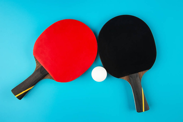 теннисные ракетки и мячик для пинг-понга на синем фоне
 - Фото, изображение