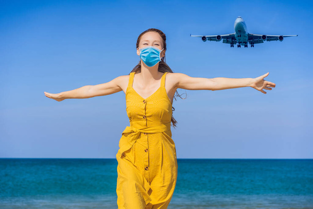 Γυναίκα με ιατρική μάσκα διασκεδάστε στην παραλία βλέποντας τα αεροπλάνα προσγείωσης. Ταξιδεύω με την ιδέα του αεροπλάνου. Χώρος κειμένου. Νήσος Πουκέτ στην Ταϊλάνδη. Εντυπωσιακό παράδεισο. Ζεστή παραλία Μάι Κάο. Καταπληκτικό. - Φωτογραφία, εικόνα