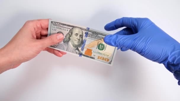 Hand of a patient giving money to a doctor and hand in blue glove giving medicine, pills, tablets in blister back, corruption and paid medicine concept, expensive treatment - Záběry, video
