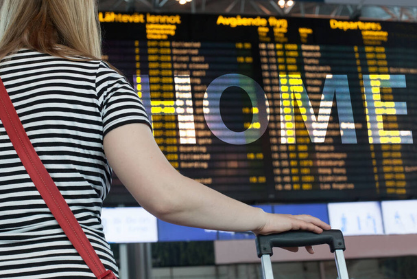 Встреча выпускников. Женщина с ручной клади в международном аэропорту терминала, глядя на информационную доску, проверяя свой рейс
 - Фото, изображение