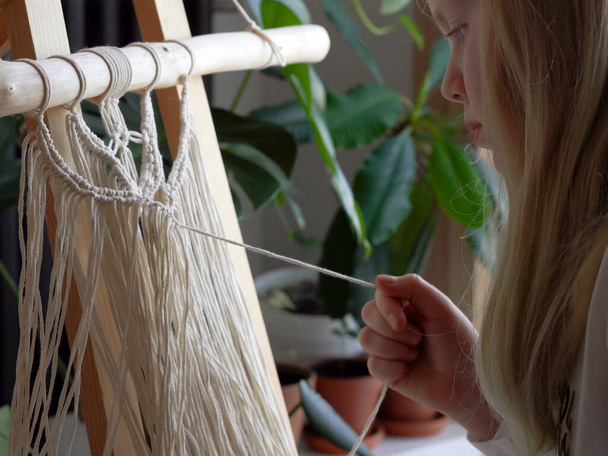 залишайся вдома. робота під час карантину дівчина у вітальні фреска ткацтво мотузок в техніці макраме
 - Фото, зображення