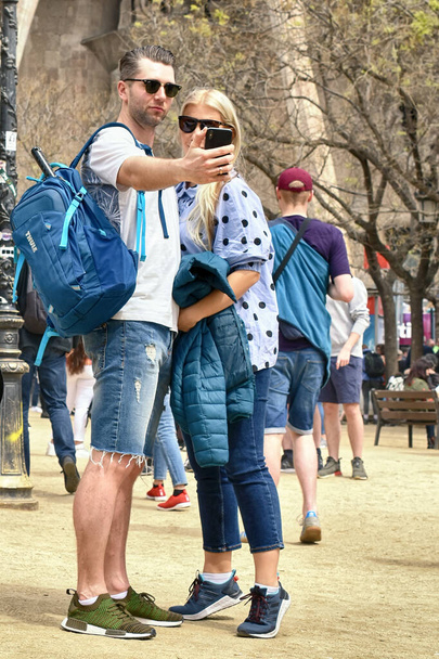 SPAIN, BARCELONA - APRIL 15, 2019: guy and girl take pictures of themselves on telephone on a city street - Valokuva, kuva