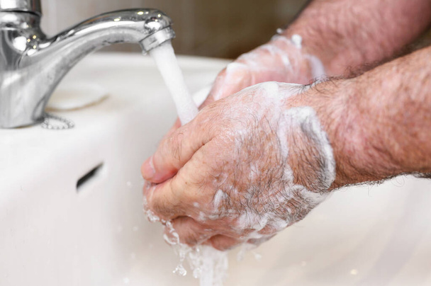Крупным планом старший человек моет руки с помощью мыльной пены, профилактики от covid19, коронавируса или бактерии. Концепция здравоохранения, 7 ступенчатая мойка рук
. - Фото, изображение