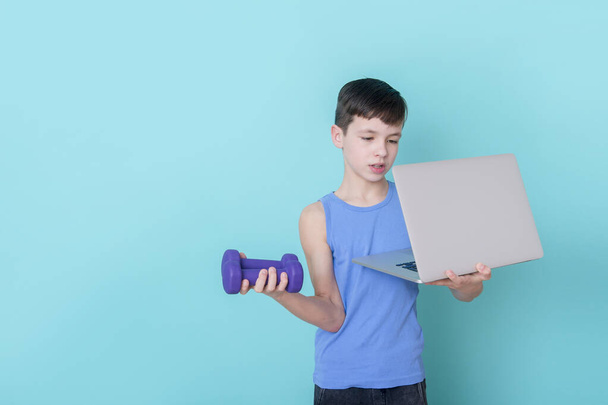 Jongen kijkt online video op laptop en doet fitnessoefeningen thuis. Workout online concept. - Foto, afbeelding