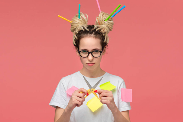 Teenager in a white shirt and glasses holding scissors in hands and felt pens in dreads. Think creative - Photo, Image