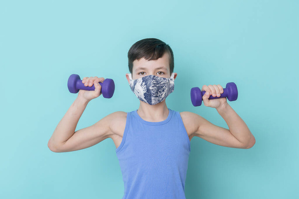 Портрет красивого мальчика-подростка с гантелями и коронавирусом. Концепция тренировок онлайн
. - Фото, изображение