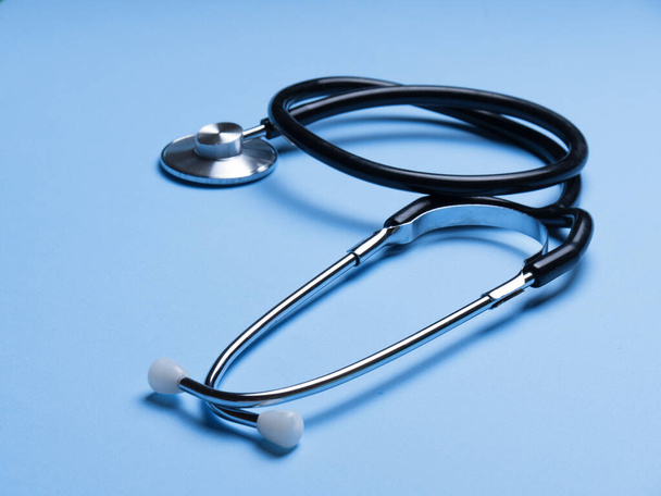 Zwarte stethoscoop voor arts diagnostische coronavirus ziekte, medisch hulpmiddel voor de gezondheid op blauwe achtergrond met kopieerruimte. Phonendoscoop en zwarte maskon paarse achtergrond. Medische instrumenten - Foto, afbeelding