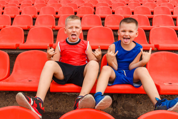 children sit in the sports stands and cheer for the team. show your tongue and shout - Photo, Image