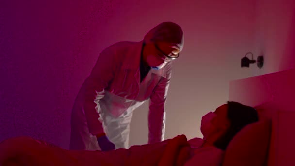 Doktor, hastane odasında virüslü hasta kadını kontrol ediyor. Hasta öksürüyor ve kötü hissediyor. - Video, Çekim