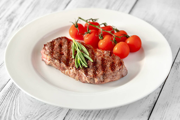Beef steak with cherry tomatoes and fresh rosemary on white plate - Foto, afbeelding