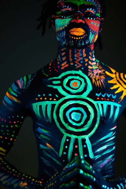 Conceptual portrait of african man painted in fluorescent UV colors - Фото, изображение