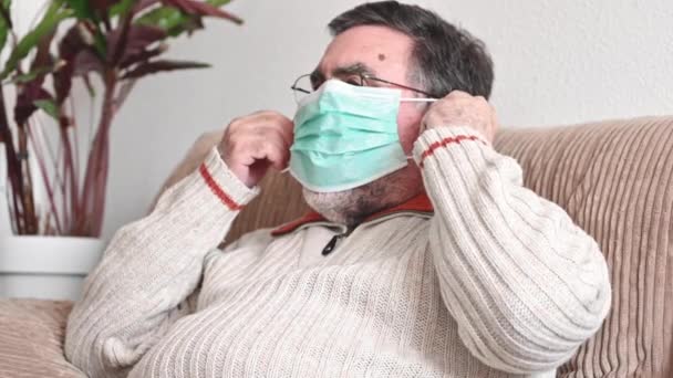Oudere man zet een medisch masker op zijn gezicht om zichzelf te beschermen tegen coronavirus pandemie.  - Video